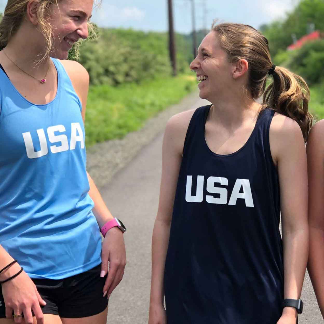 Two laughing women wearing the USA Field Hockey Performance Tanks.