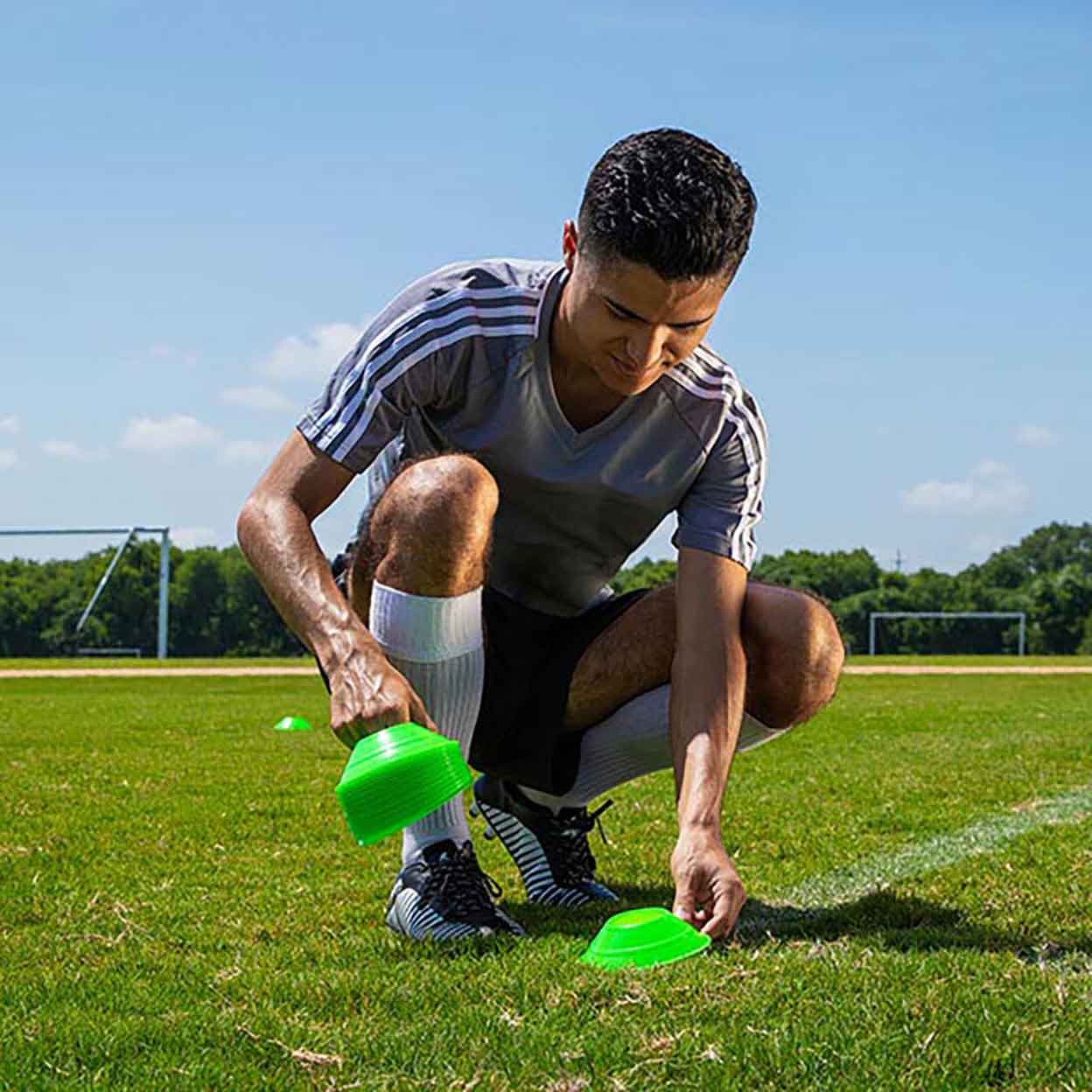 a man placing the Mini Neon Disc Cones on a field