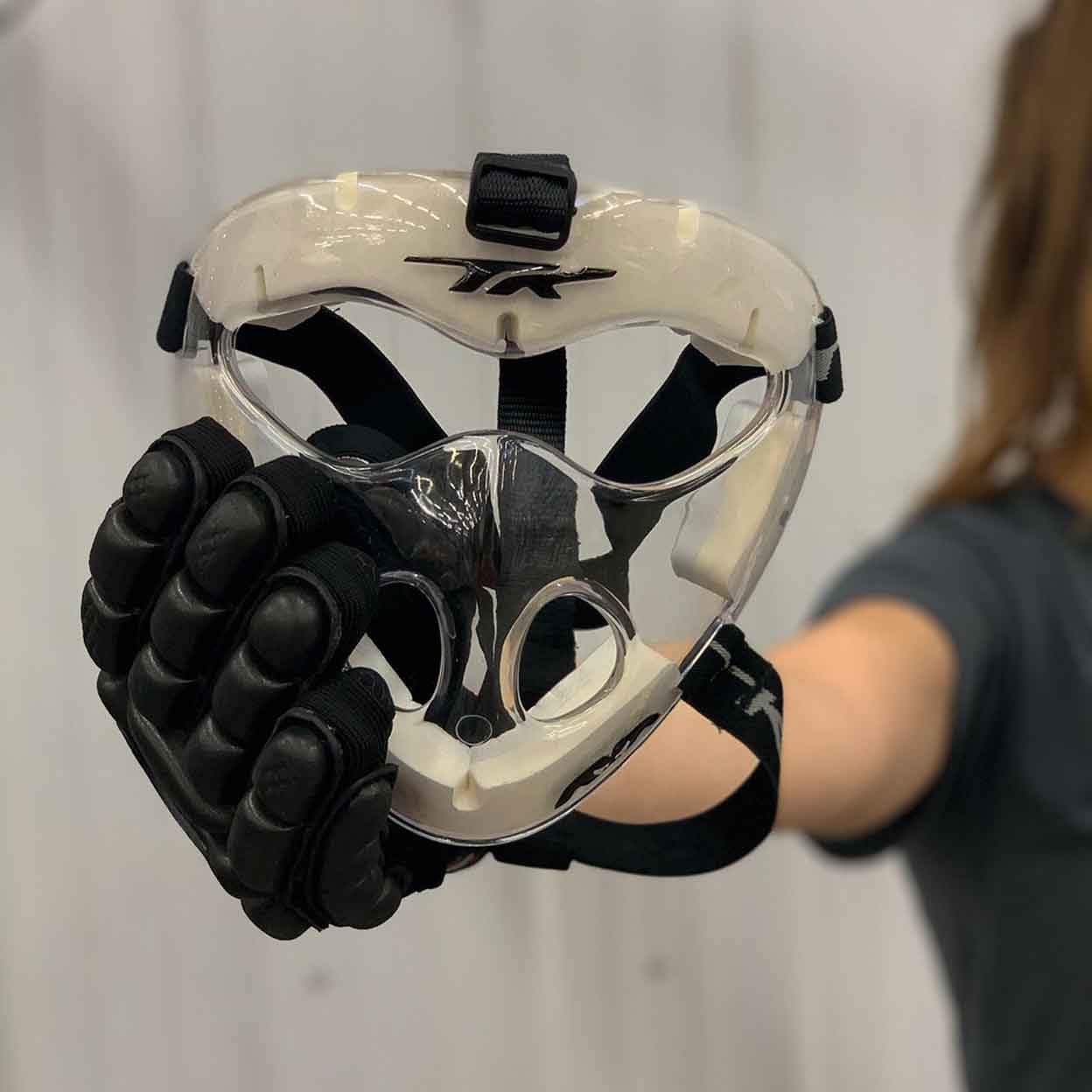 Gloved hand holding the clear TK2 Field Hockey Player Mask