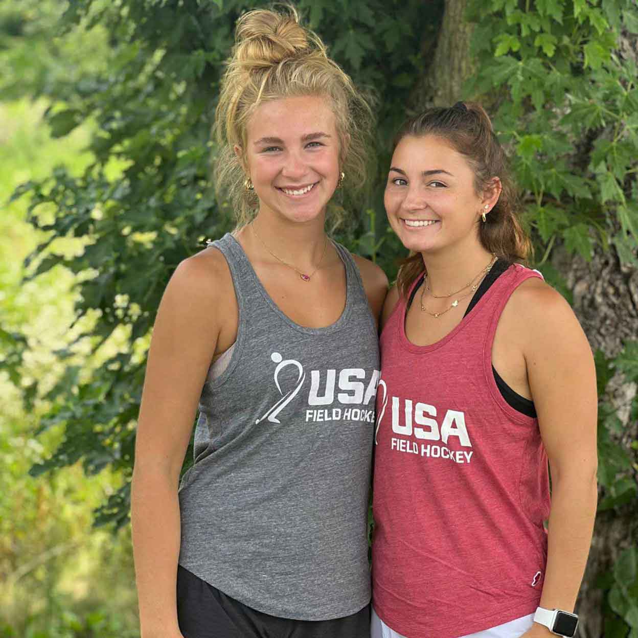 Two girls wearing the USA Field Hockey Intramural Tank and smiling.