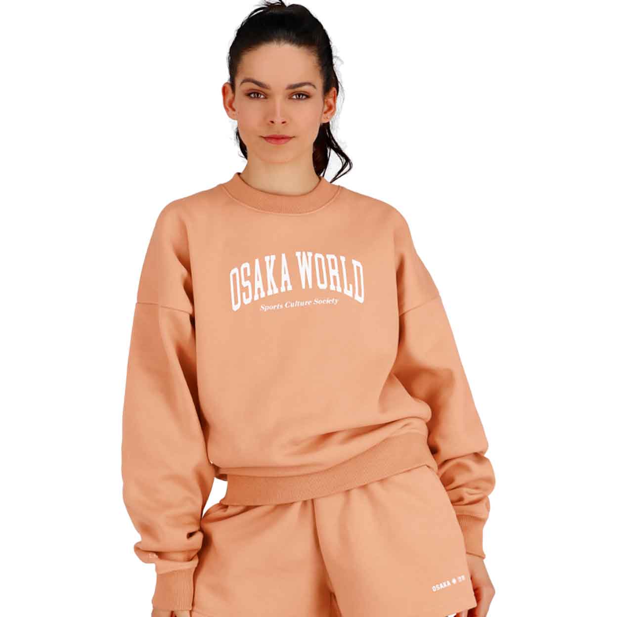 The peach Osaka Women's Crewneck Sweatshirt on a model with hands at sides.