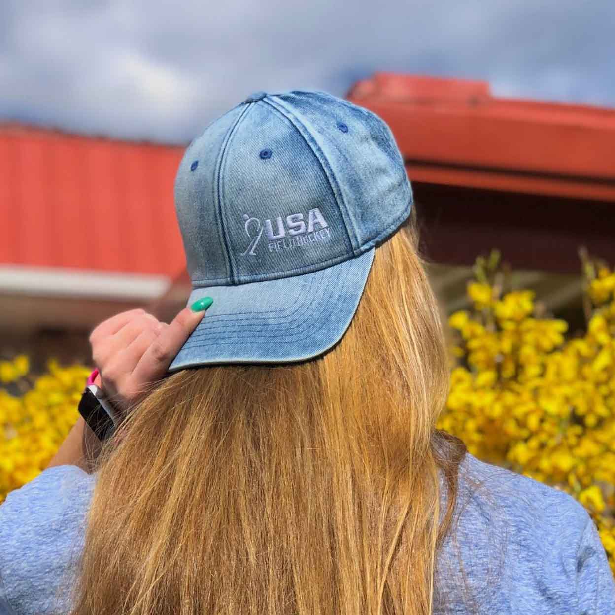 girl wearing the USA Field Hockey Hybrid Blue Denim Hat backwards with hand on the brim