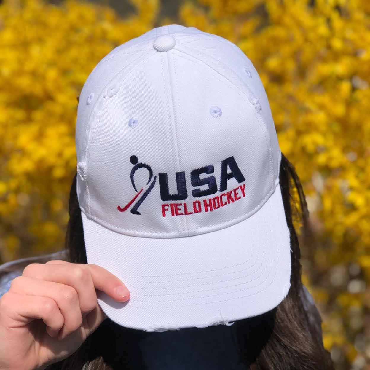 hand on the brim of a white USA Field Hockey Hybrid Distressed Denim Hat