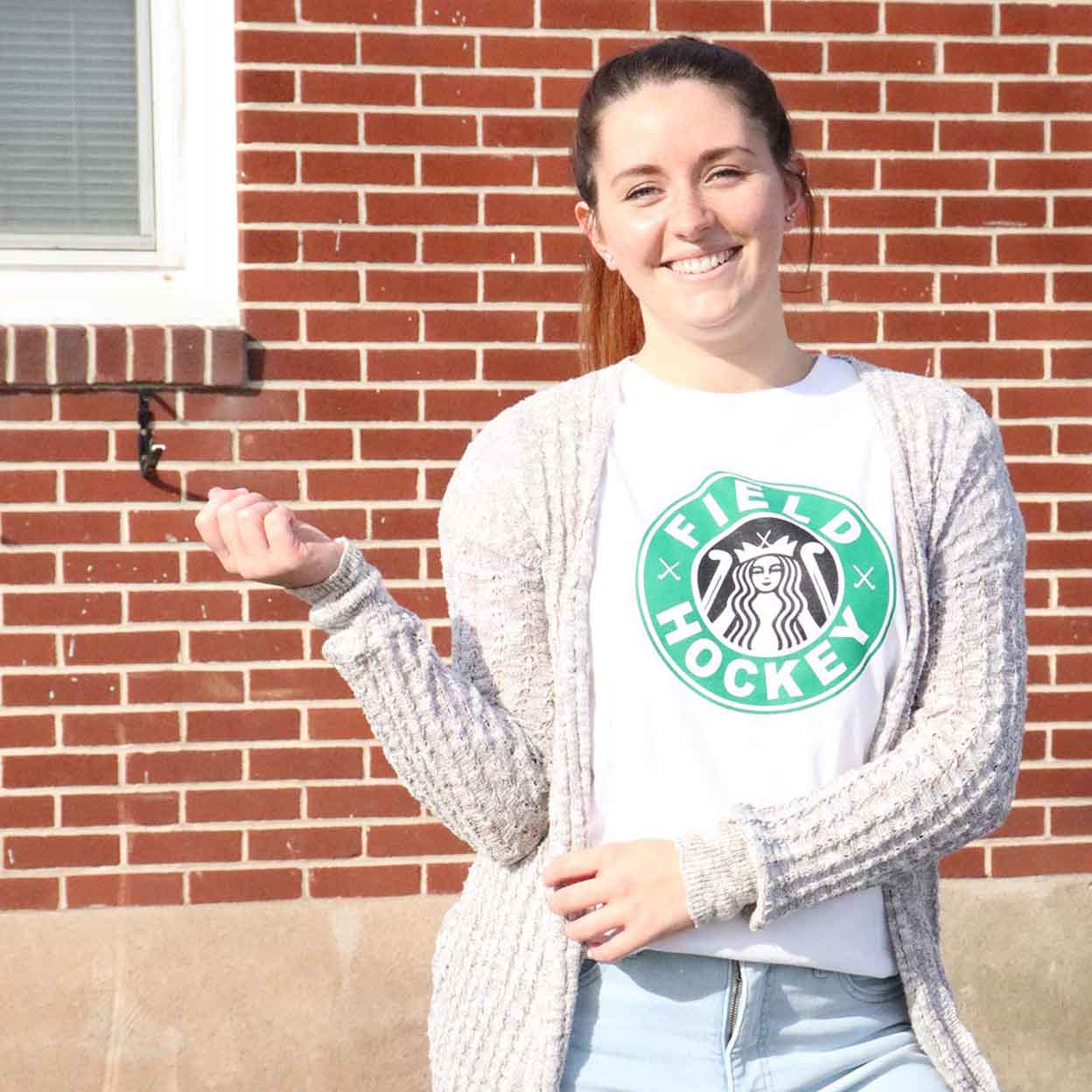 smiling girl wearing the Field Hockey Addict Unisex Tee