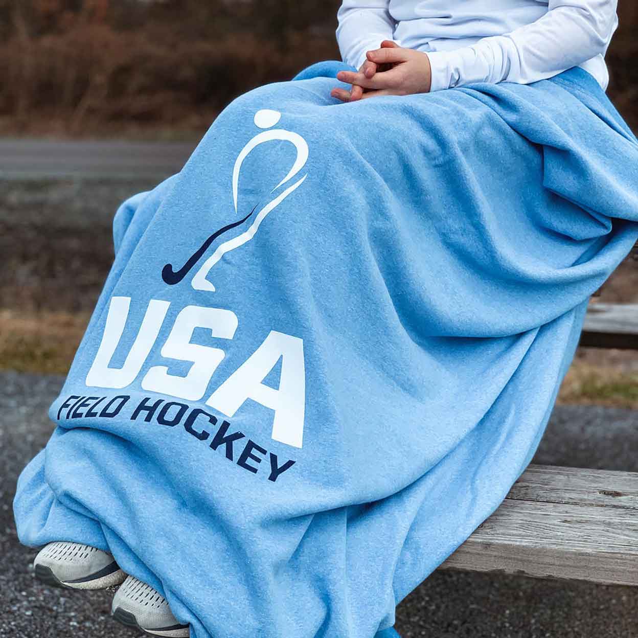 Blue USA Field Hockey Sweatshirt Blanket wrapped around legs of a person sitting on bleachers